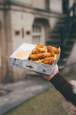 Fish & Fries box against a classic Amsterdam canal house staircase