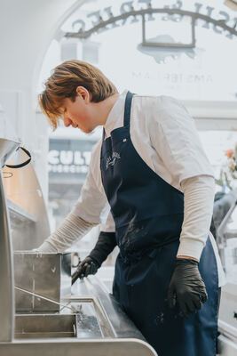 Chef working at the fryer, backlit by the arched storefront window