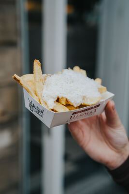 Vleminckx fries with Parmesan held up in front of the Fish & Fries storefront